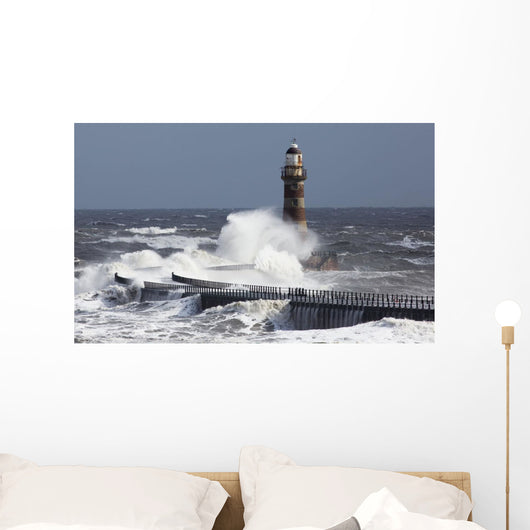Waves crashing into a lighthouse Wall Mural
