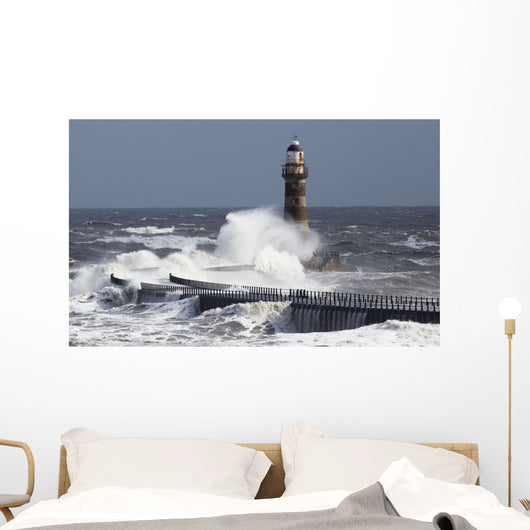 Waves crashing into a lighthouse Wall Mural