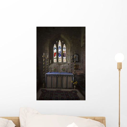 Stained glass windows and a table surrounded with candles in a church Wall Mural