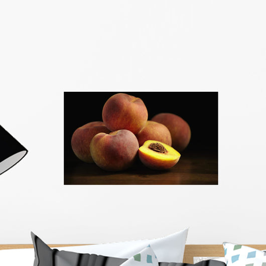 Peaches sitting on a wooden table, one cut in half Wall Mural