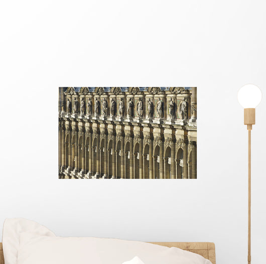 Ornate facade of a building with columns and statues of men in a row Wall Mural