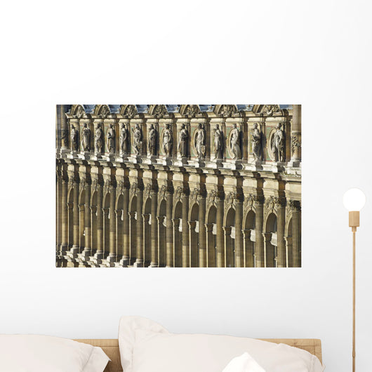 Ornate facade of a building with columns and statues of men in a row Wall Mural