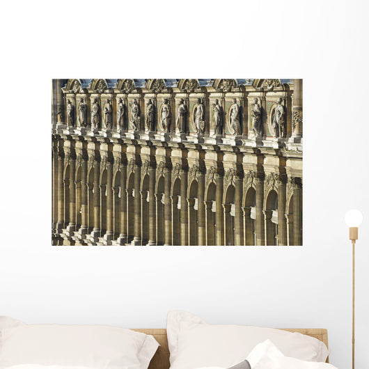 Ornate facade of a building with columns and statues of men in a row Wall Mural