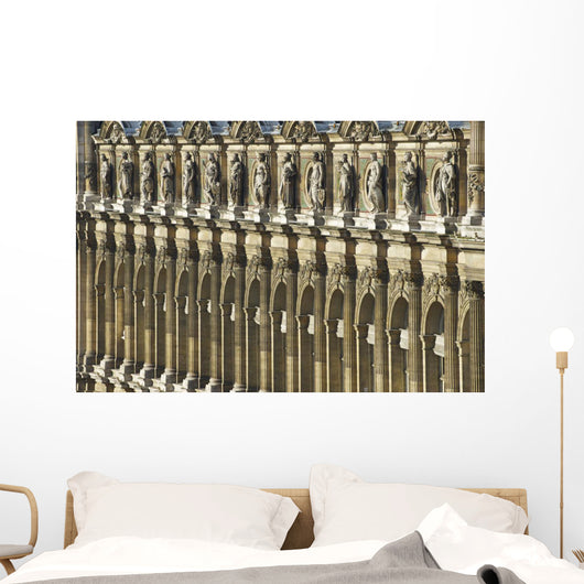 Ornate facade of a building with columns and statues of men in a row Wall Mural