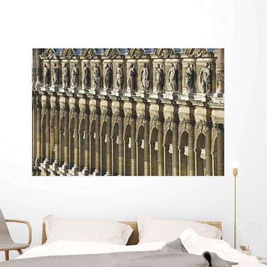 Ornate facade of a building with columns and statues of men in a row Wall Mural