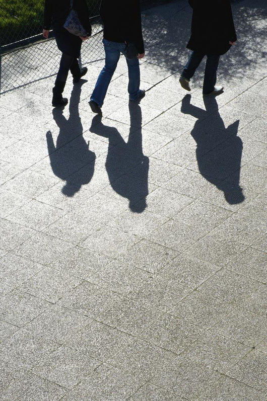 Pedestrians and their shadows on a walkway Wall Mural