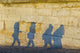Shadows of pedestrians cast on a wall Wall Mural