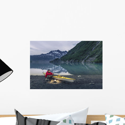 Man reading on a electronic tablet while camping with a kayak Wall Mural
