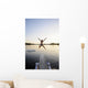 A swimmer jumps off a diving board as the sun sets over a lake Wall Mural