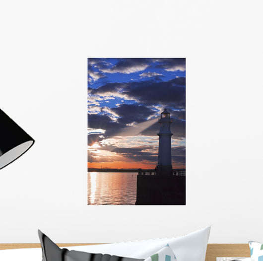 Lighthouse at sunset with light beam Wall Mural