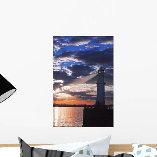 Lighthouse at sunset with light beam Wall Mural