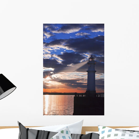 Lighthouse at sunset with light beam Wall Mural