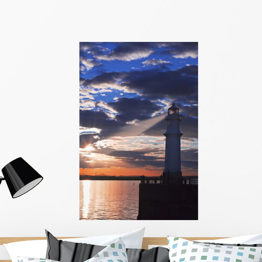 Lighthouse at sunset with light beam Wall Mural