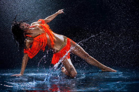 Woman dancing under rain in orange dress. Studio Wall Mural