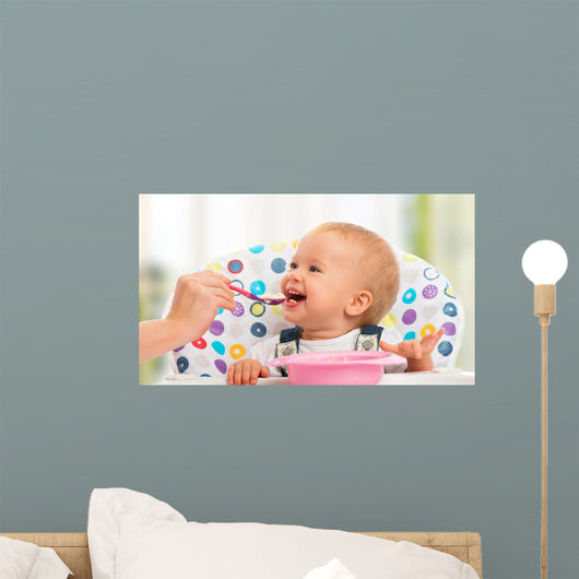 happy mother feeds funny baby from spoon