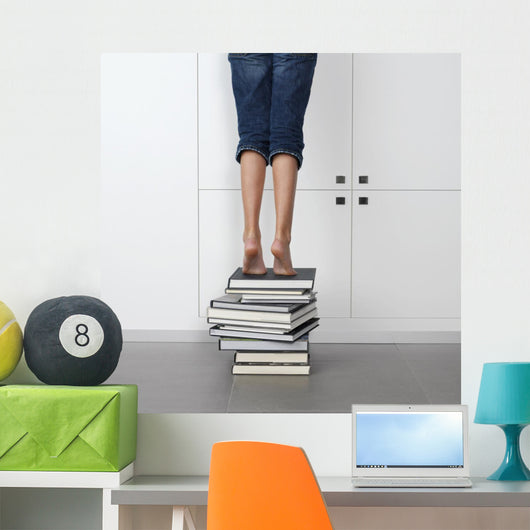 teenage girl standing on top of a stack of books Wall Mural