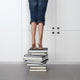 teenage girl standing on top of a stack of books Wall Mural