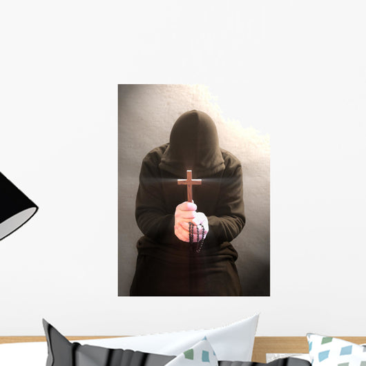 A monk praying with a rosary and crucifix in his hand. Wall Mural
