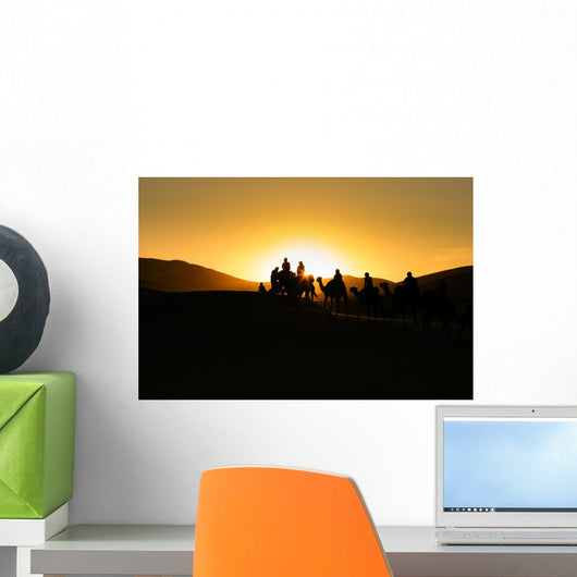 Silhouettes of tourists riding camels on dunes Wall Mural