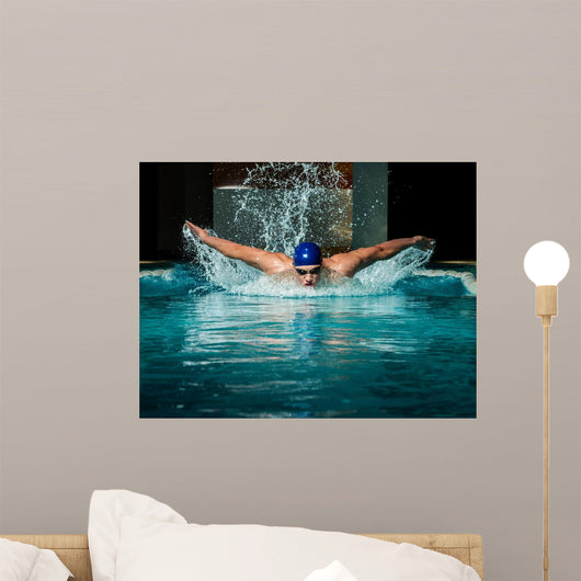 Muscular young man in blue cap in swimming pool