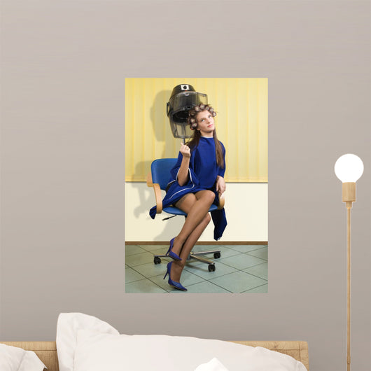 young woman sitting under a hairdryier with roller on head