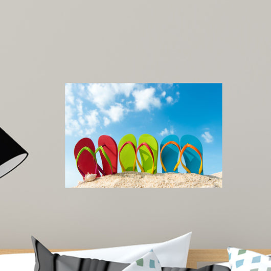 Row of colorful flip flops on beach against sunny sky