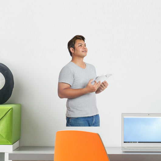 Asian man reading a book looking up with day dreaming Wall Decal