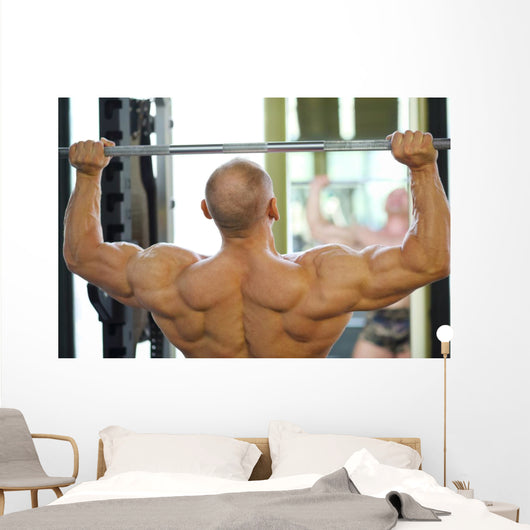 Back of Bodybuilder Raising Barbell in Gym Hall before Mirror Wall Mural