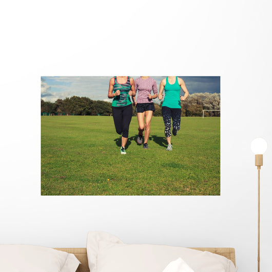 Three women running in the park Wall Mural
