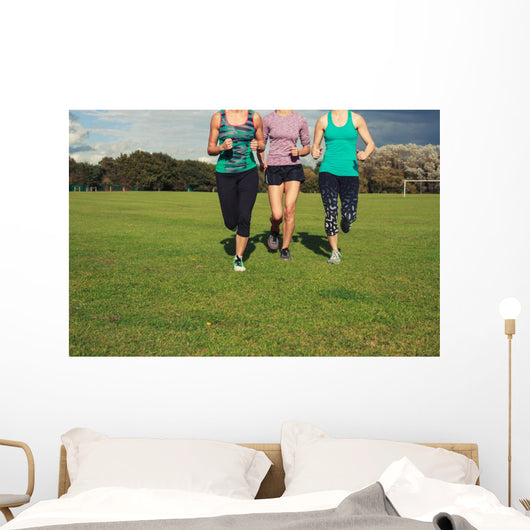 Three women running in the park Wall Mural