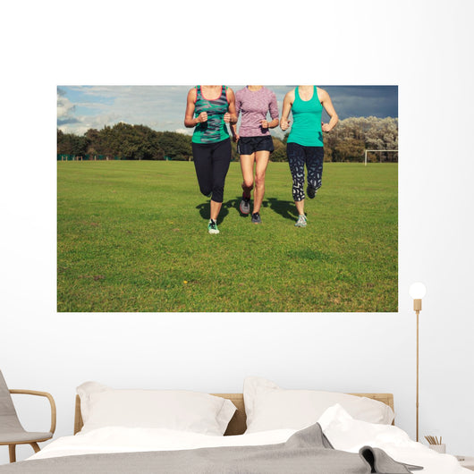 Three women running in the park Wall Mural