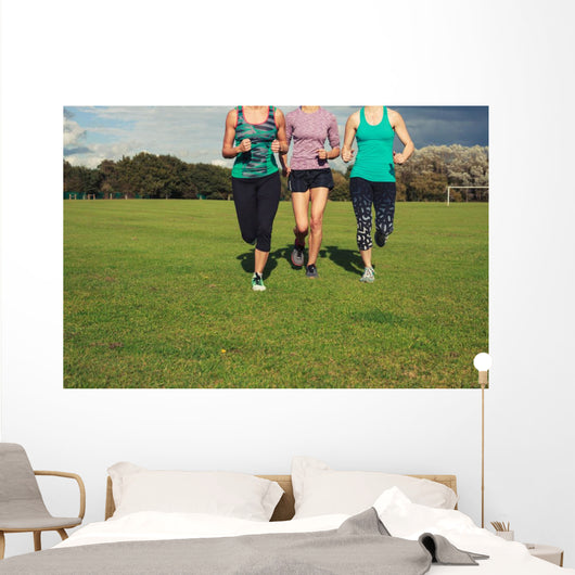 Three women running in the park Wall Mural