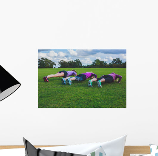 Three women doing push ups in park Wall Mural