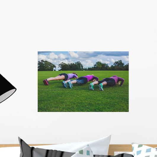 Three women doing push ups in park Wall Mural