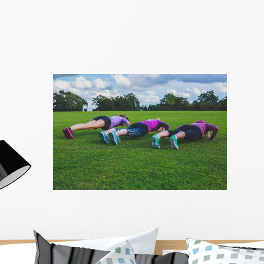 Three women doing push ups in park Wall Mural