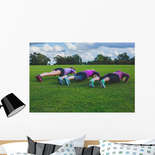 Three women doing push ups in park Wall Mural