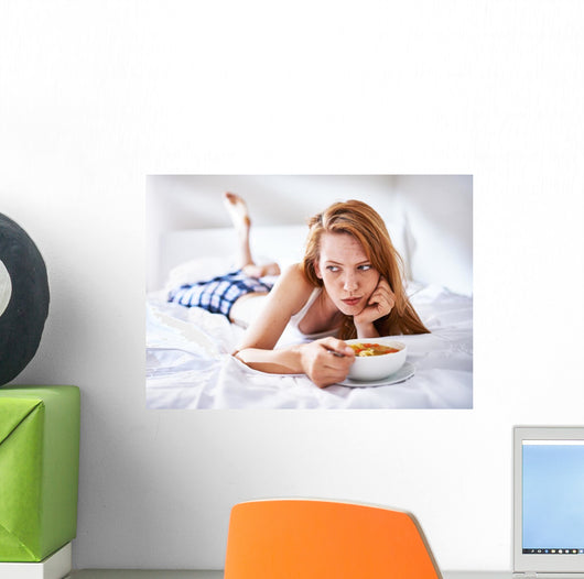woman in bed eating chicken noodle soup while sick Wall Mural