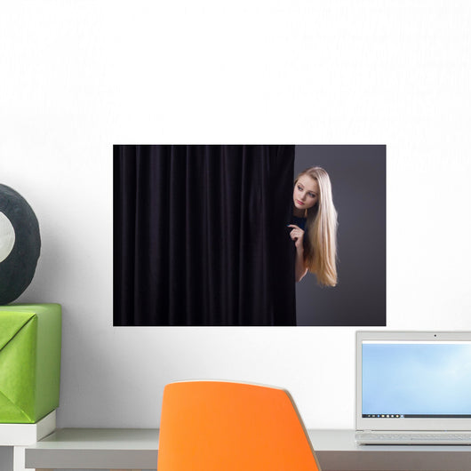 Frightened girl hiding behind a curtain. Wall Mural