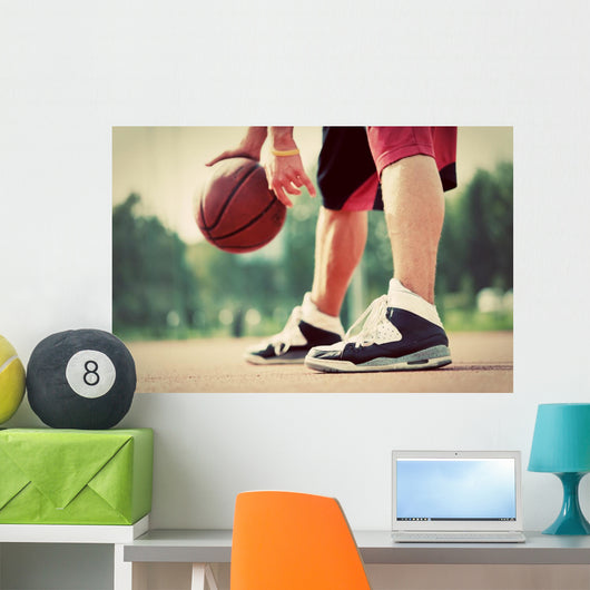 Young man on basketball court dribbling with bal Wall Mural