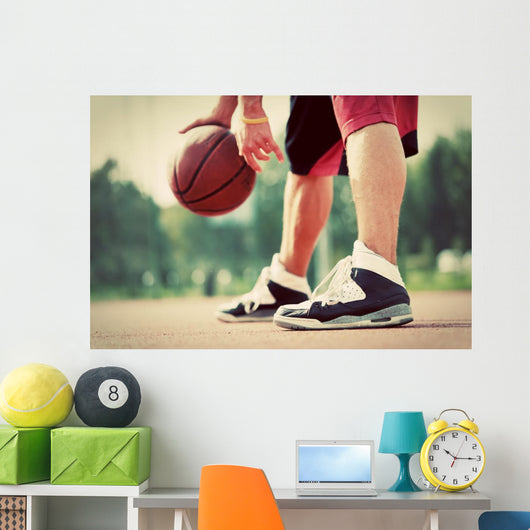 Young man on basketball court dribbling with bal Wall Mural