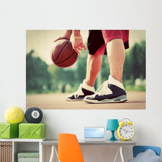 Young man on basketball court dribbling with bal Wall Mural