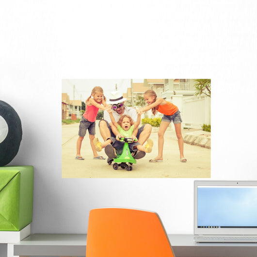 father and children playing near a house at the day time Wall Mural