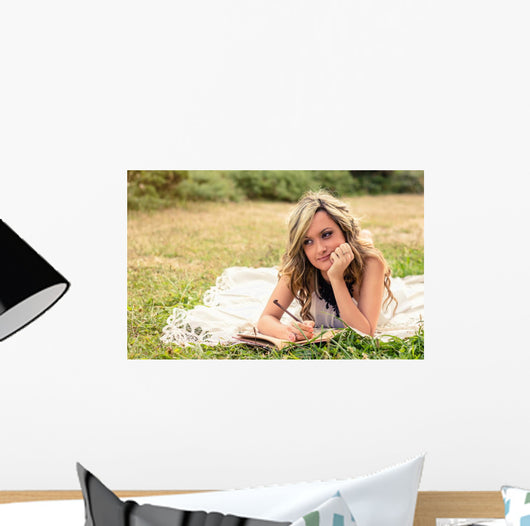 Romantic girl writing in a diary lying down outdoors Wall Mural
