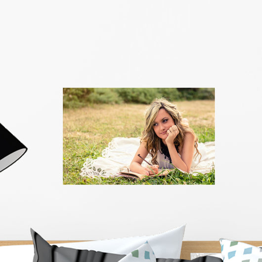 Romantic girl writing in a diary lying down outdoors Wall Mural
