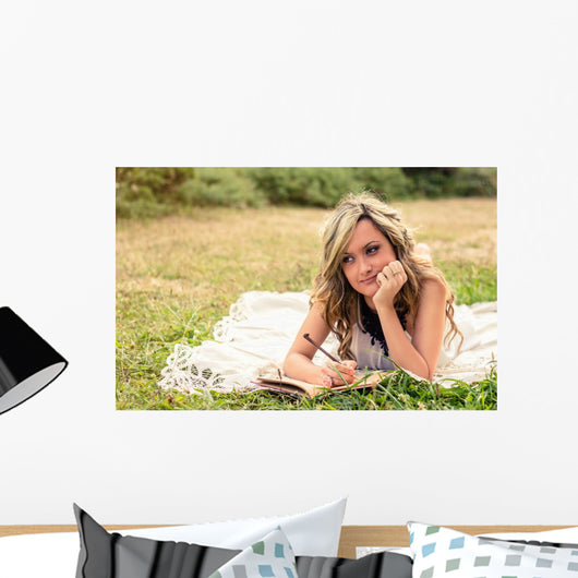 Romantic girl writing in a diary lying down outdoors Wall Mural