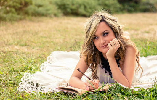 Romantic girl writing in a diary lying down outdoors Wall Mural