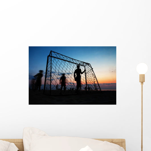 Boys playing football on the beach in summer Wall Decal