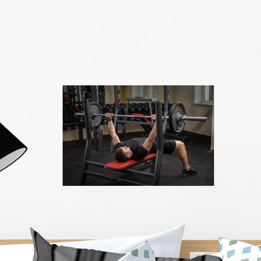 young man doing bench press workout in gym Wall Decal