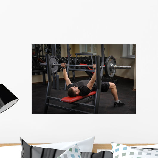 young man doing bench press workout in gym Wall Decal