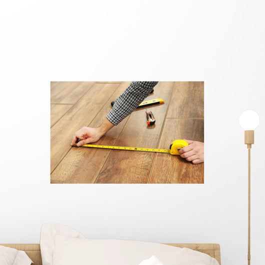 Carpenter worker installing laminate flooring in the room Wall Decal